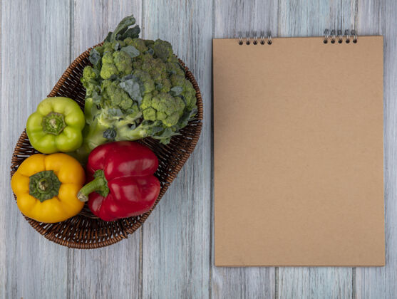 视图蔬菜的顶视图 如花椰菜和胡椒在篮子里 木制背景上有便笺簿 有复印空间垫木头篮子