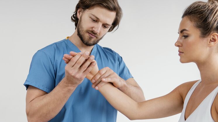 治疗男性骨科治疗师正在检查女性患者的手腕肌肉骨骼男人病人