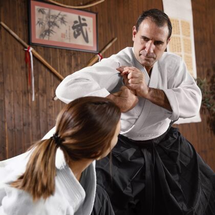 柔道低角度的男武术教练和女学员在练习厅训练训练战斗女人