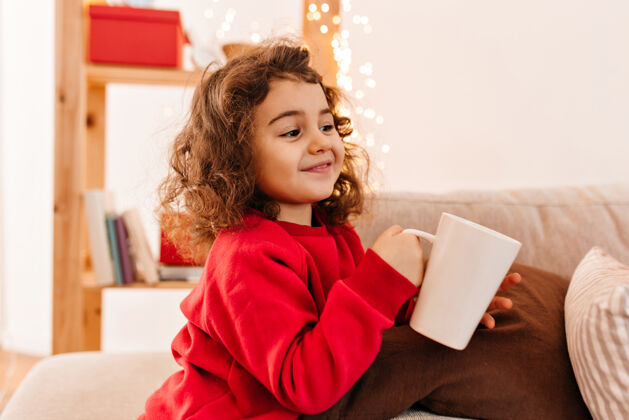 沙发快乐的小孩喝茶可爱的卷发小孩拿着杯子枕头沙发发型