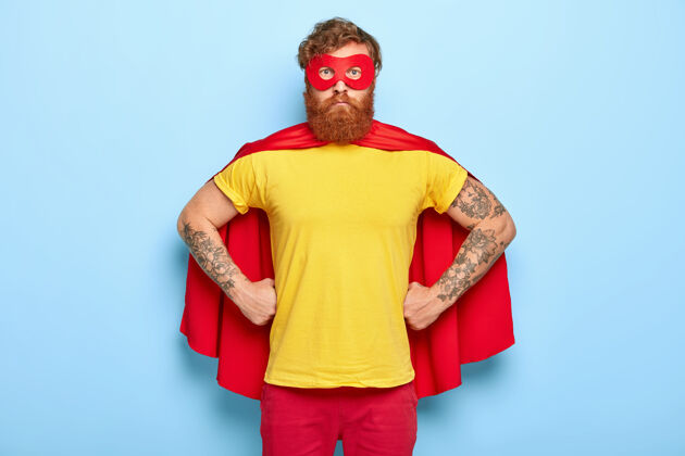 胡子穿着超级英雄服装的严肃男性照片 双手放在腰上 拥有非凡的才能衣服表情斗篷