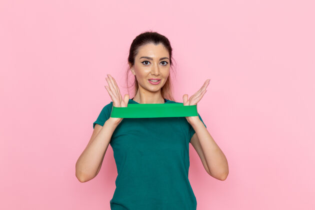 减肥正面图年轻女性拿着绿色绷带在粉红色的墙上美容运动运动员锻炼苗条女性人运动