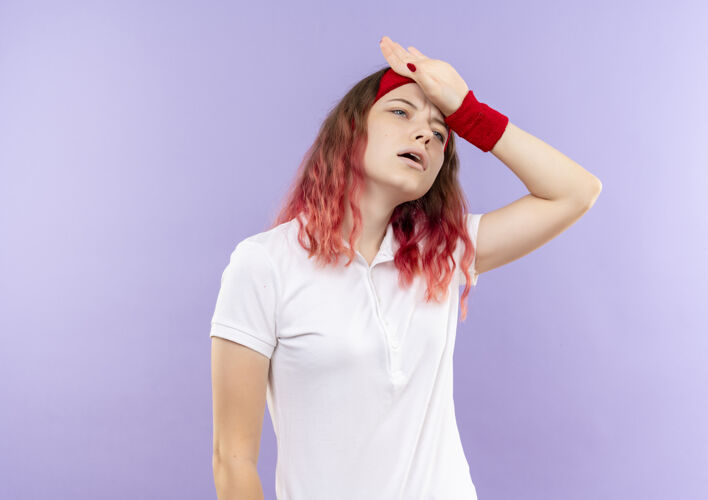 头年轻的运动型女人 看起来不舒服 头痛 站在紫色的墙上碰头运动人运动