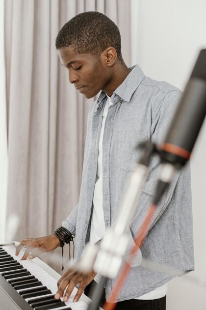 表演帅哥男音乐家在家玩电子键盘侧视图创造者男人音乐家