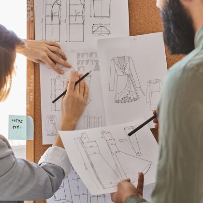 工作室时装设计师在创意板上为新的服装系列咨询计划创意男性设计师