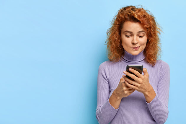 和平可爱的红发女士肖像集中在智能手机设备 检查邮箱 在线聊天服装互联网姜