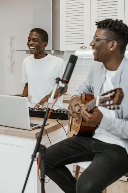 乐器笑脸男音乐家在家里弹吉他和电子键盘艺术家技能男人