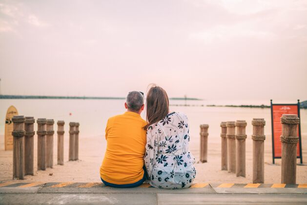 海洋日落时分一对夫妇坐在海滩附近的特写镜头浪漫女性情侣