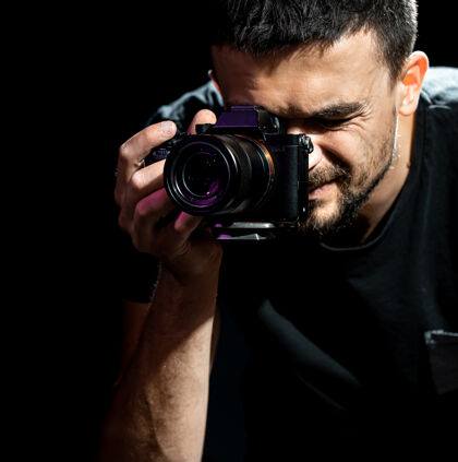 镜头这个男人拿着一个照相机 准备拍照摄影师看着照相机的取景器拍照黑暗创意拍摄