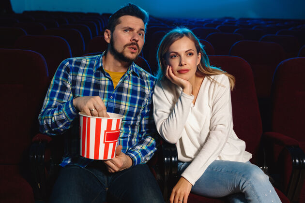 情侣迷人的年轻白种人夫妇在电影院 房子或电影院看电影看起来富于表现力 惊讶和情绪化独自坐着玩关系 爱情 家庭 周末时间电影院成人椅子