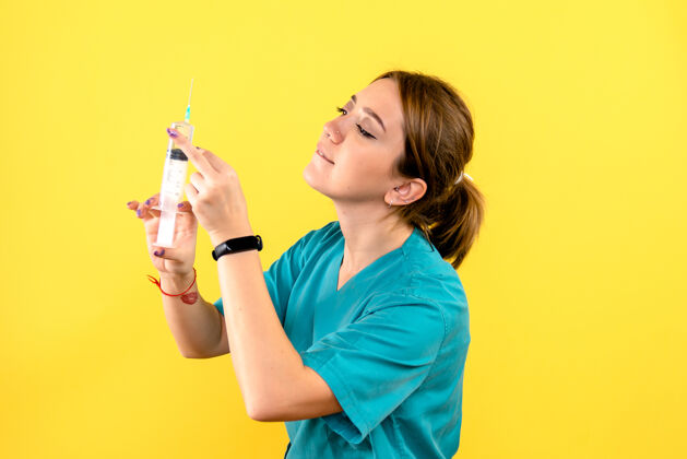 漂亮黄色墙上的女兽医拿着针剂的正视图持有健康成人