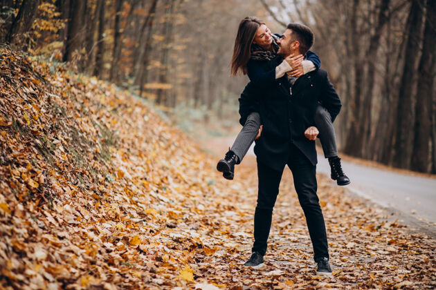 男人一对年轻夫妇在秋天的公园里散步快乐的女人女人浪漫