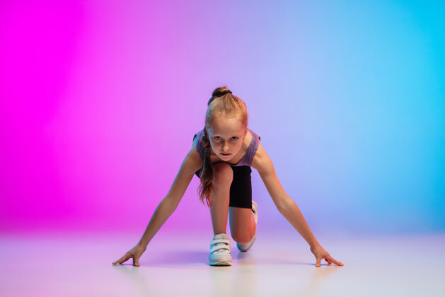 冠军健康少女 专业跑步者 慢跑者 在霓虹灯下的渐变粉蓝色背景上运动隔离运动 运动 活力和动态的概念 健康的生活方式运动员儿童慢跑