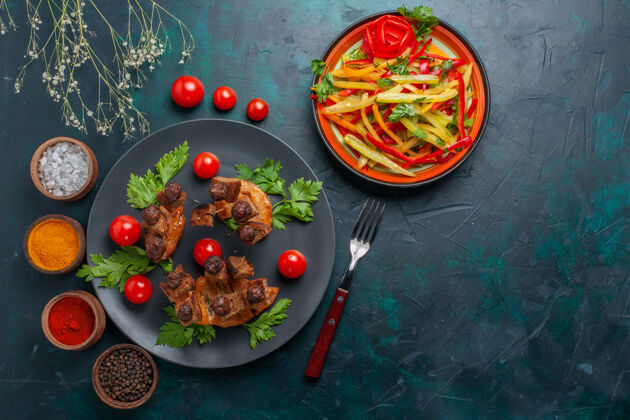 生的顶视图炸肉片配切片蔬菜沙拉和调味料 深蓝色桌上蔬菜餐食物肉类餐健康胡椒菜肉