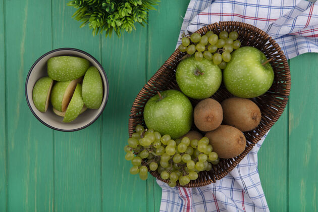 绿色顶视图绿色苹果楔形碗与猕猴桃和葡萄在绿色的背景篮子视图碗葡萄