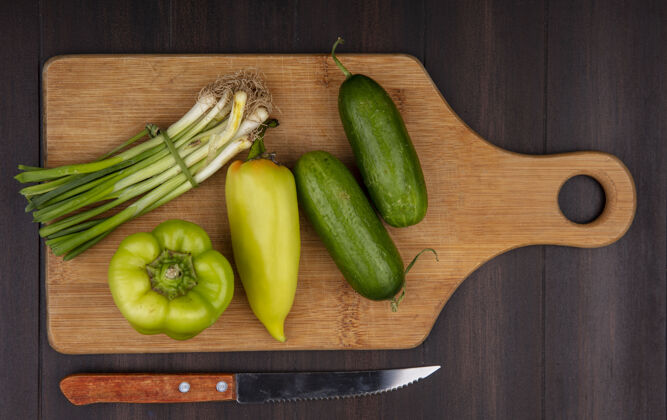 视野顶视图：在木制背景上用刀在砧板上切洋葱 黄瓜和青椒菜板刀新鲜