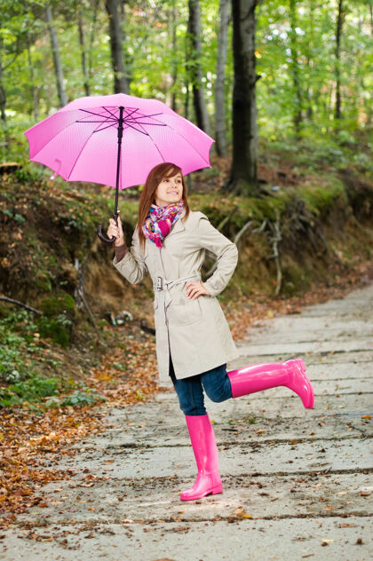 表达积极可爱的年轻女子在雨后玩得很开心天气围巾雨伞