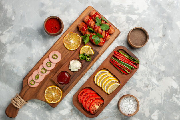 顶部顶视图不同的调味品与香肠和蔬菜在白色桌上一餐食物蔬菜餐厅生的盘子