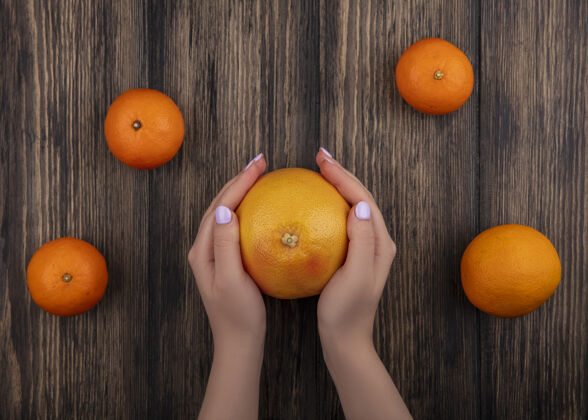 新鲜顶视图女人拿着柚子和橘子在木制背景上水果木材顶部