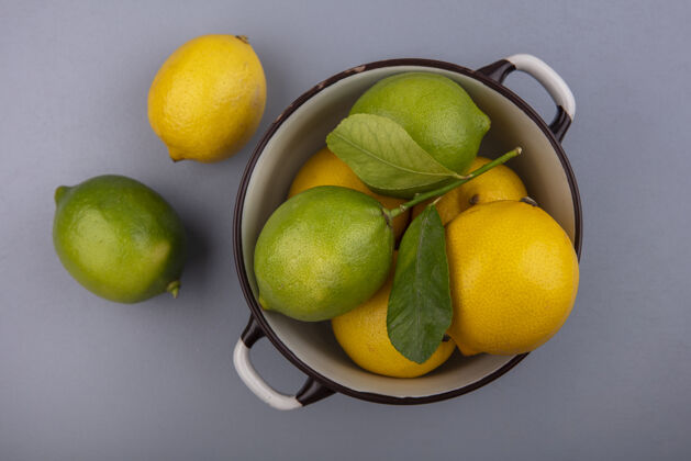 视野在灰色背景的平底锅中俯瞰柠檬和酸橙灰色新鲜水果