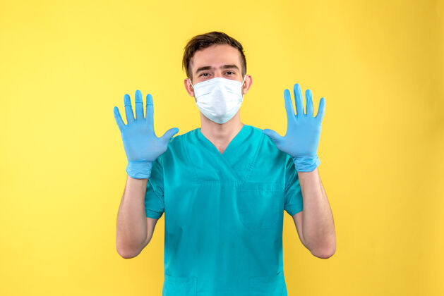 外科黄色墙上戴着手套和面罩的男医生的正面图胡子情绪男性