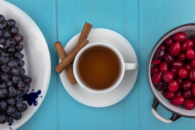 浆果一杯茶的顶视图与肉桂棒和山茱萸浆果在一个蓝色的木制背景碗棍子视图山茱萸