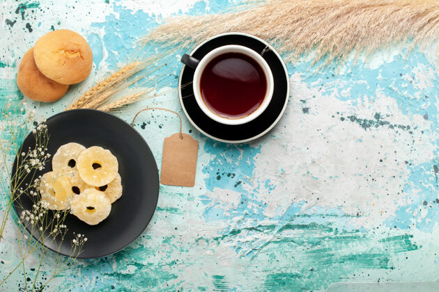 生的顶视图干菠萝戒指配上一杯茶放在蓝色的桌子上蛋糕烤水果饼干甜糖饼干戒指饼干干的