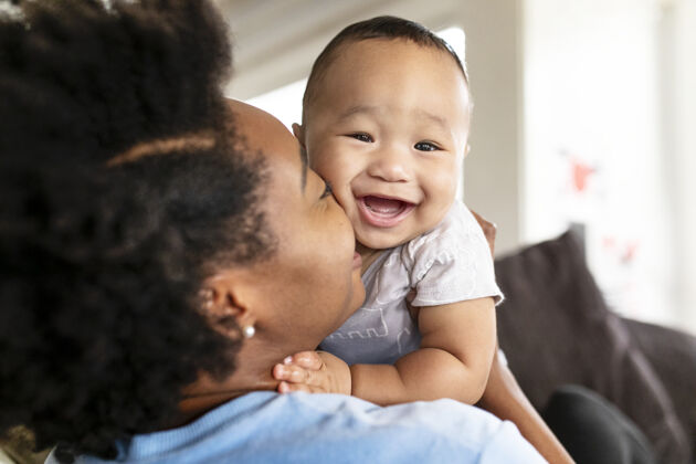 妈妈快乐的非洲裔美国母亲亲吻她的儿子儿童护理在一起母亲