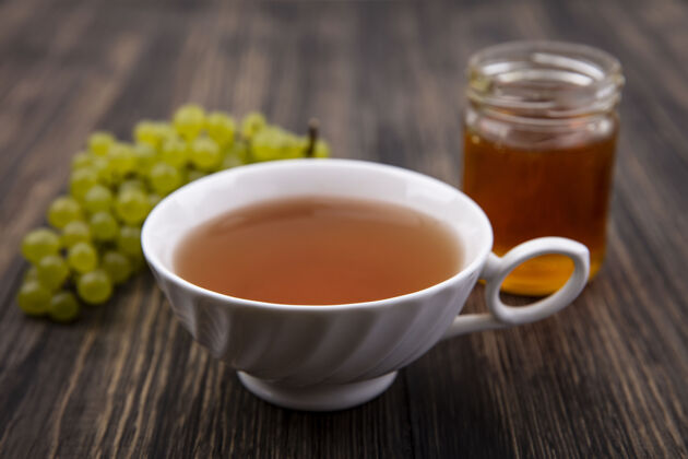 饮料正面是一杯茶 绿色葡萄和蜂蜜放在木制背景的罐子里风景罐子茶