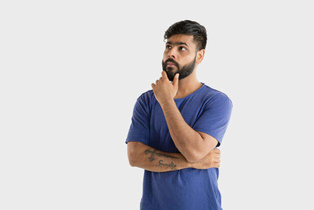 肖像美丽的男性半身肖像隔离在白色的工作室背景年轻感性的印度教男子在蓝色衬衫面部表情 人类情感 广告概念思考或选择姿势消极人物