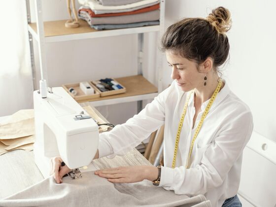 女女裁缝在工作室工作的侧视图服装缝纫机针线