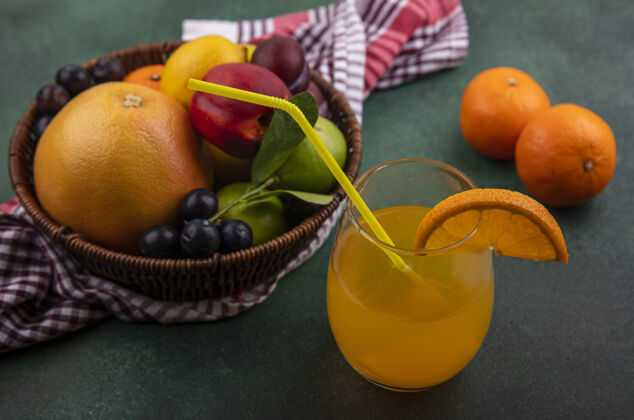 风景侧视图橙汁在一个杯子里 葡萄柚 柠檬 桃子 樱桃 李子 橘子和李子在一个绿色的篮子里柠檬葡萄柚绿色