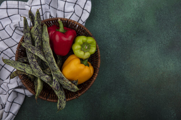 铃铛顶视图复制空间绿色背景上的格子毛巾上的篮子里的青豆和甜椒方格食物新鲜