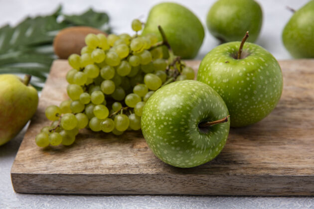 景观侧视图绿色苹果与绿色葡萄在一个白色背景的立场绿色苹果立场