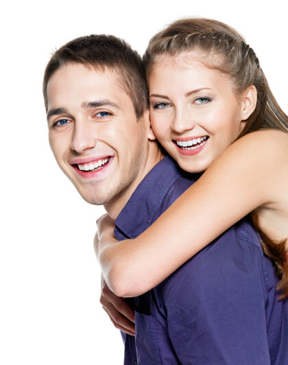 快乐美丽的年轻幸福的夫妇在白墙上拥抱在一起爱