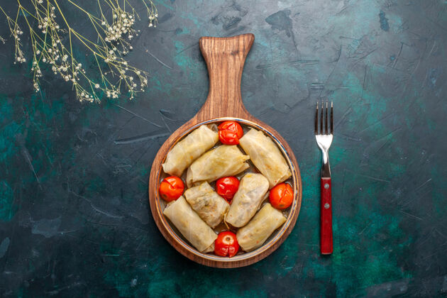 西红柿俯瞰美味的多尔玛肉食卷心菜和西红柿在深蓝色桌上肉食晚餐蔬菜菜肴烹饪生的木勺晚餐