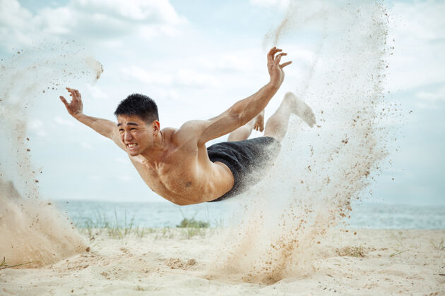 手臂年轻健康的男子运动员在海滩上做深蹲成人交叉人