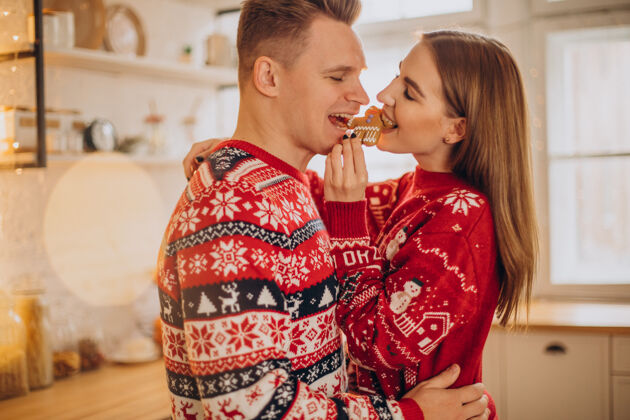 圣诞快乐夫妻俩在厨房吃圣诞饼干浪漫女朋友圣诞树