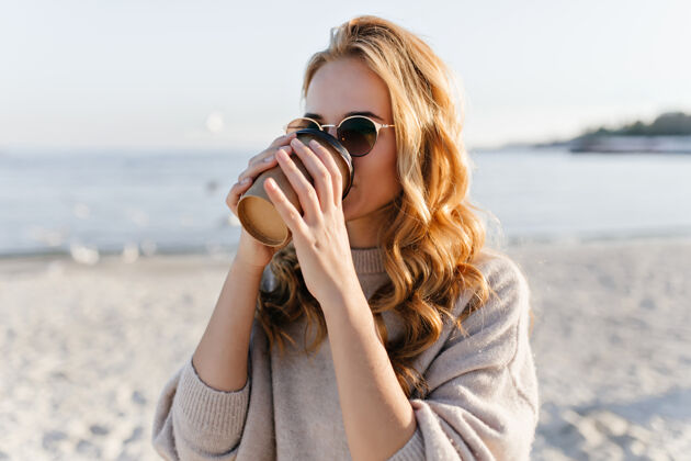 假期美丽的女人戴着优雅的太阳镜在海边休息梦幻女模特在秋日的户外写真户外年轻海岸