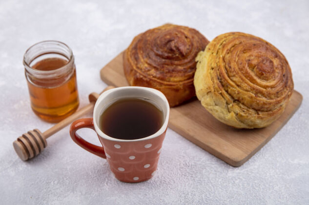 果敢侧视图阿塞拜疆传统糕点戈加尔在木制厨房板上 一杯茶和蜂蜜放在一个白色背景的玻璃罐上目标视图木头