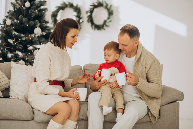 圣诞礼物一家人带着小儿子在家里的圣诞树旁过圣诞节女人男婴庆祝