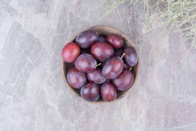 水果紫色李子放在石头背景的木碗里美味李子健康