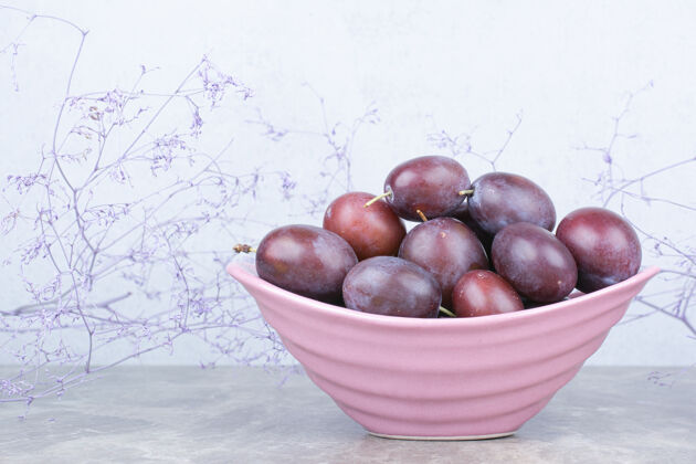 新鲜一碗新鲜的李子放在石桌上紫色水果美味