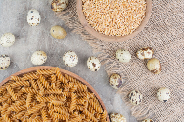 生物把意大利面放在一个木盘里 上面放着小麦粒和鹌鹑蛋餐厅厨房产品