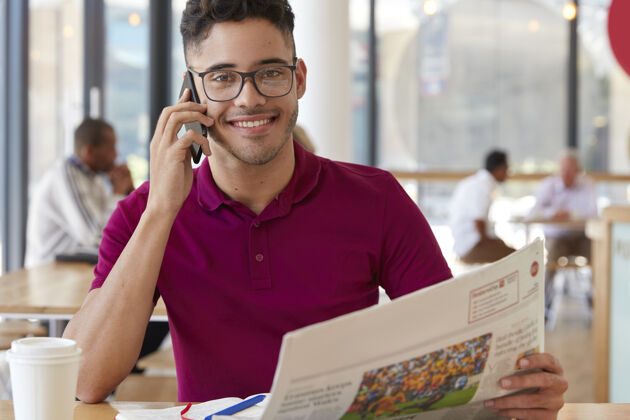 休闲心情愉快的企业家 戴眼镜 打电话 看报纸 和朋友讨论新闻 在舒适的餐厅喝咖啡职业自由职业者高兴新闻微笑