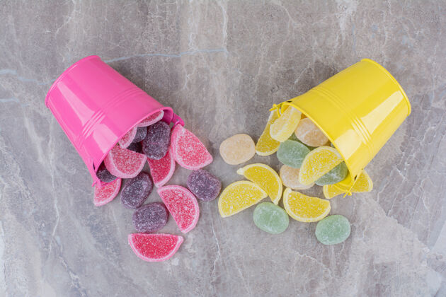 黄色黄色和粉色的桶 大理石背景上有糖果酱甜味糖桶