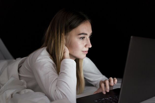 小玩意女孩晚上在床上用笔记本电脑水平科技青少年