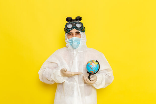 特殊正面图：黄色办公桌上 一位身着特殊套装的男科学工作者手里拿着一个小圆球前面西装圆