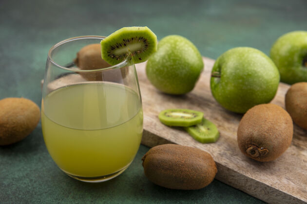 食物侧视图苹果汁在一个玻璃与绿色的背景板上的绿色苹果和猕猴桃板水果苹果