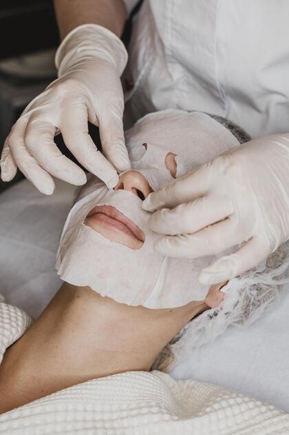 护理在水疗中心接受皮肤面膜治疗的女人美容垂直水疗